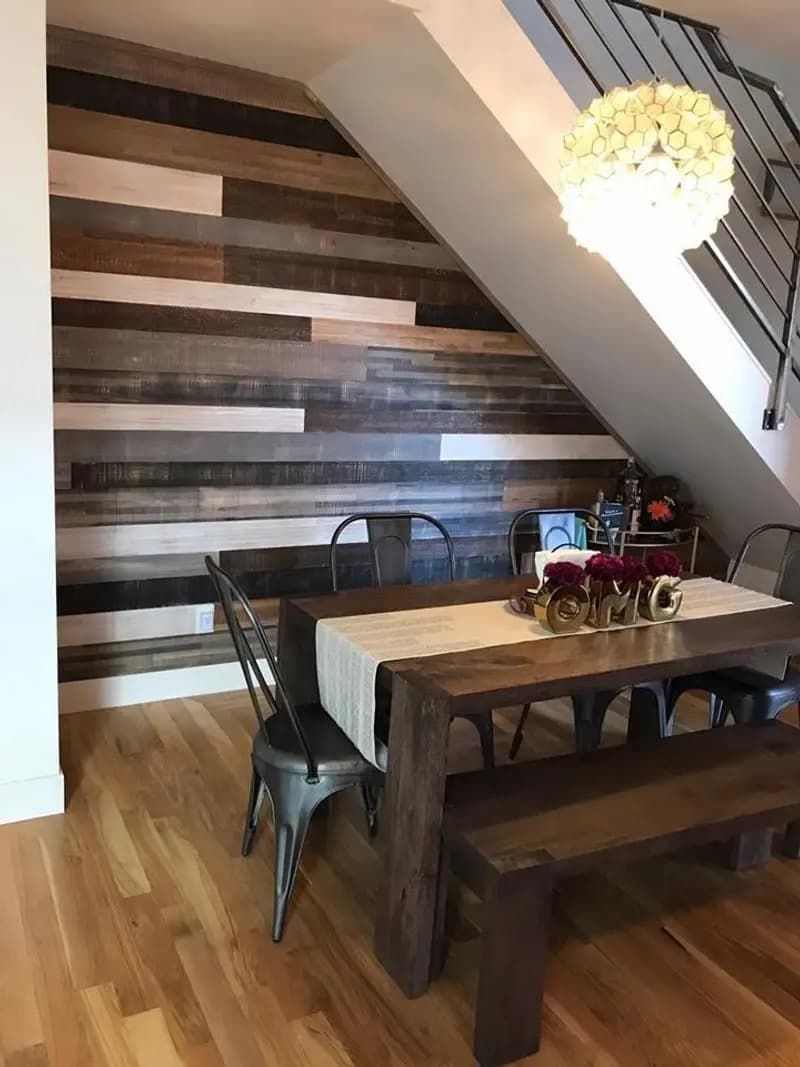 a table with chairs and a chandelier in front of a wood wall