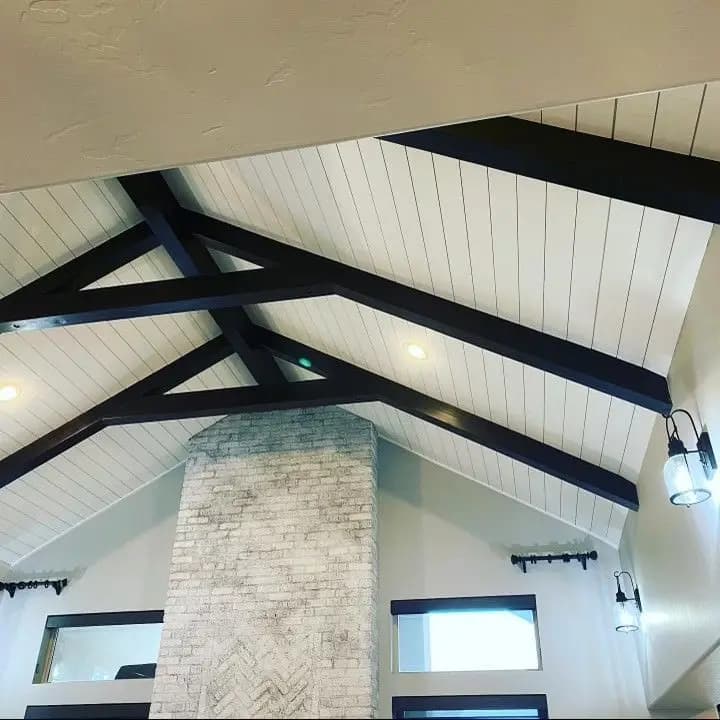 a ceiling with black beams and a brick chimney